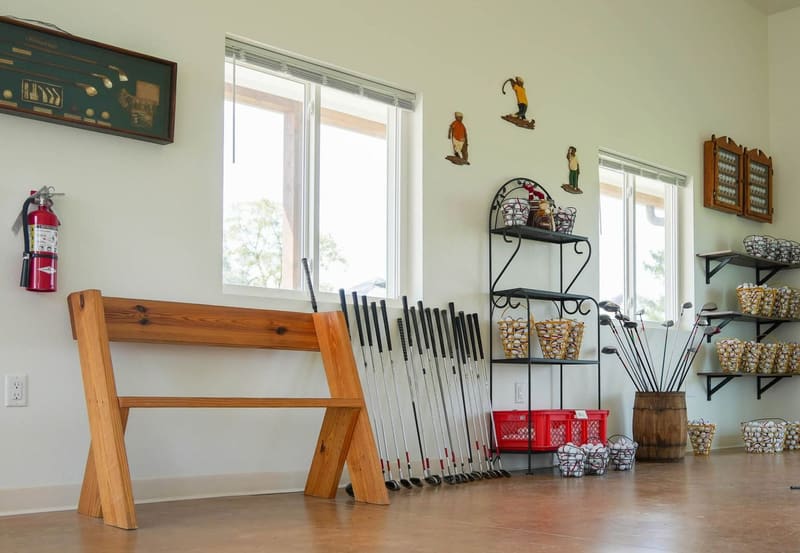 Inside the new clubhouse: free loaner clubs lined up along the wall next to shelves of filled ball baskets